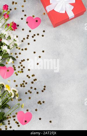 Grußkarte zum Valentinstag. Komposition mit Geschenk, Blumen, rosafarbenen Herzen und kleinen Sternen auf blauem Hintergrund. Draufsicht. Platz für Textflaches Layout Stockfoto