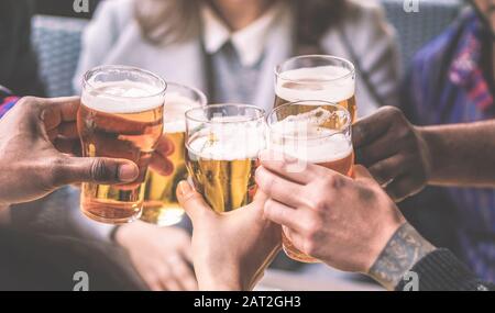 Eine Gruppe von Freunden, die eine Bierbrille im englischen Pub der Brauerei genießen - Jugendliche jubeln im Bar-Restaurant - Freundschafts- und Jugendkonzept - Warmer Vintag Stockfoto