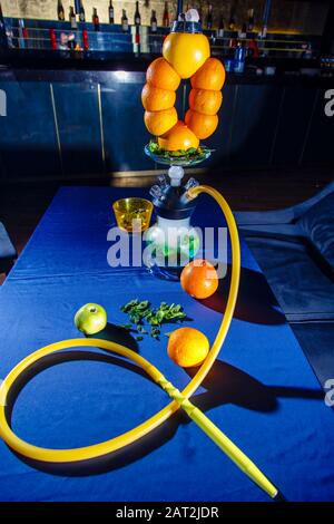 Hookah auf Orangen. Citrus Hookah. Hookah mit runder klarer Glühlampe mit rotem Schnaps. Eine Schüssel Hookah aus Orangen. Viel Rauch. Stockfoto