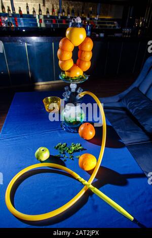 Hookah auf Orangen. Citrus Hookah. Hookah mit runder klarer Glühlampe mit rotem Schnaps. Eine Schüssel Hookah aus Orangen. Viel Rauch. Stockfoto