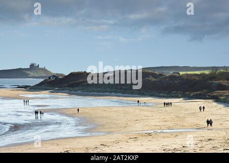 Silhouette entfernter Wandergruppen an einem sandigen Strand, Low Newton, Northumberland UK. Stockfoto