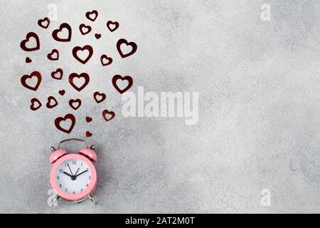 Zeitkonzept Wecker in blauem Hintergrund mit rotem Herz. Minimalistischer Stil. Platz für Text. Valentinstag Hintergrund. Designelement für Begrüßung Stockfoto