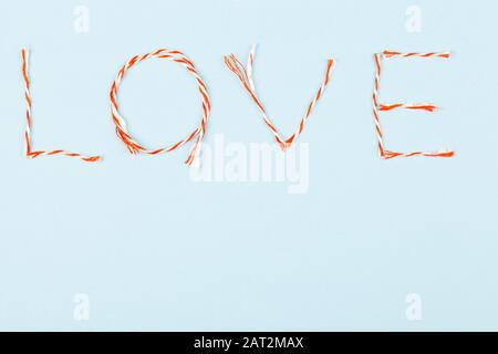 Valentines Day Komposition mit Love Word und Konfetti auf blauem Hintergrund. Flaches Lay, Draufsicht. Designelement für Grußkarten, Verkauf Stockfoto
