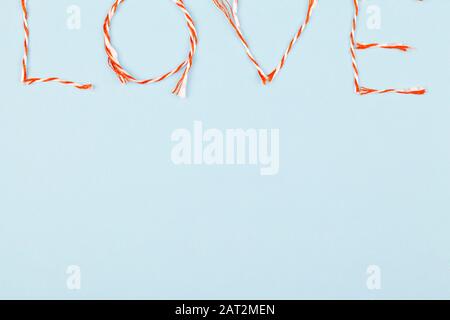 Valentines Day Komposition mit Love Word und Konfetti auf blauem Hintergrund. Flaches Lay, Draufsicht. Designelement für Grußkarten, Verkauf Stockfoto