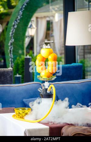 Hookah auf der Orange. Orange Hookah. Hookah mit einem runden durchsichtigen Kolben, in dem in Scheiben geschnittene Orangen und Minzblätter in roter Lauge schweben. Die Kapuzenbuge Stockfoto