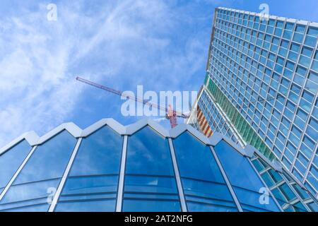 Große Baustelle einschließlich mehrerer Krane auf einen Gebäudekomplex mit klaren, blauen Himmel und die Sonne Stockfoto
