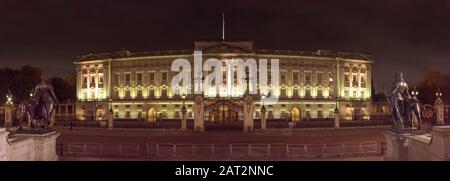 Panoramaaussicht auf die spektakuläre Außenfassade der Residenz der Königin von England, Buckingham Palace, Westminster, Großbritannien, leuchtet nachts auf. Stockfoto