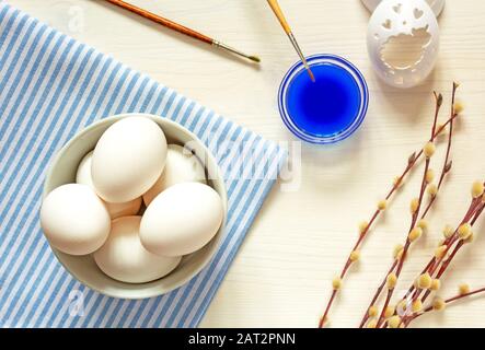 Vorbereitung auf die Feier zu Ostern, Frühlingsstimmung. Ganze, rohe weiße Eier, die zum Färben und Verzieren in einer weißen Schüssel mit Bürsten, Schablone zubereitet werden Stockfoto