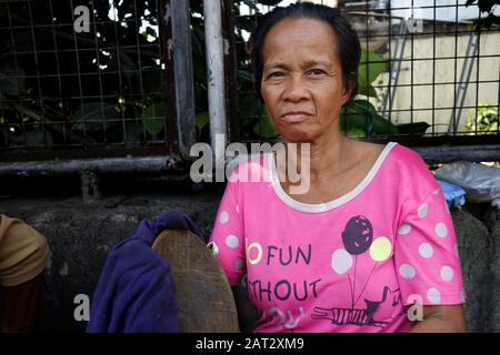 Antipolo-Stadt, Philippinen - 29. Januar 2020: Eine Erwachsene philippinische Frau, die auf einem Bürgersteig sitzt, posieren für die Kamera. Stockfoto