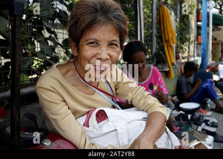 Antipolo-Stadt, Philippinen - 29. Januar 2020: Eine Erwachsene philippinische Frau, die auf einem Bürgersteig sitzt, posieren für die Kamera. Stockfoto