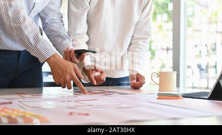 Die zugeschnittene Aufnahme des UX UI Designer Meeting Teams wird auf dem Schreibtisch geplant. Stockfoto