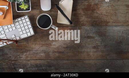 Platz für Kopien, flacher Büroschreibtisch mit Laptop, Notizbuch, Bleistift, Kaktus und Kaffeetasse auf einem alten Holztisch im Landhausstil. Stockfoto