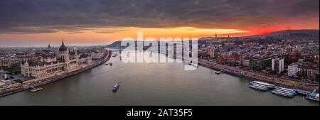 Budapest, Ungarn - Das ungarische Parlament baut auf einem großen Panoramafoto mit wunderschönem farbenfrohem Winter-Sonnenuntergang auf. Szechenyi-Kettenbrücke, Stockfoto