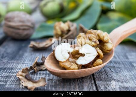 Walnüsse und Nusskernel liegen in einem Löffel auf einem rustikalen alten Holztisch. Körner von Walnüssen. Walnüsse ernten. Stockfoto