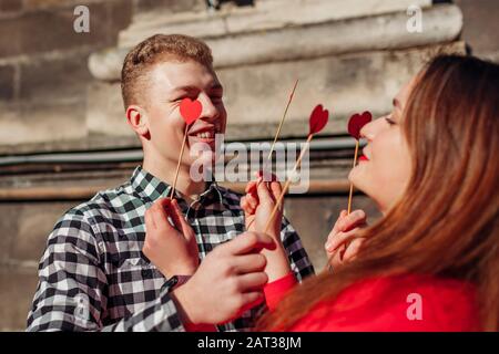 Valentinstag Fotostand Requisiten. Mann und Frau verstecken die Augen hinter roten Herzen. Paare lieben es, Spaß zu haben Stockfoto
