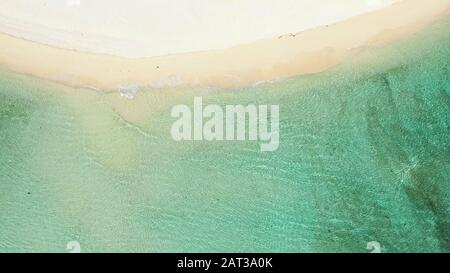 Sanfte blaue Meereswelle an einem sauberen sandigen Strand, Draufsicht. Transparente Lagune und weißer Sand. Sommer- und Urlaubskonzept. Stockfoto