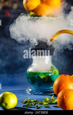 Hookah auf der Orange. Orange Hookah. Hookah mit einem runden durchsichtigen Kolben, in dem in Scheiben geschnittene Orangen und Minzblätter in roter Lauge schweben. Die Kapuzenbuge Stockfoto