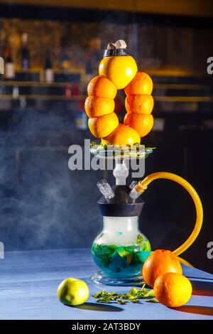 Hookah auf der Orange. Orange Hookah. Hookah mit einem runden durchsichtigen Kolben, in dem in Scheiben geschnittene Orangen und Minzblätter in roter Lauge schweben. Die Kapuzenbuge Stockfoto