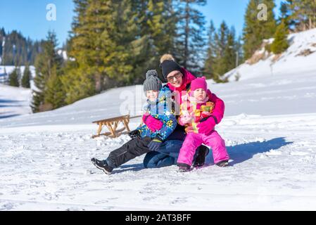 Mutter hält Kinder in den Armen auf dem Schnee. Konzept für einen Winterurlaub und eine glückliche Familie Stockfoto