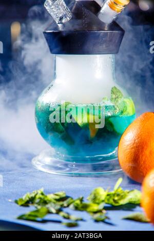 Hookah auf der Orange. Orange Hookah. Hookah mit einem runden durchsichtigen Kolben, in dem in Scheiben geschnittene Orangen und Minzblätter in roter Lauge schweben. Die Kapuzenbuge Stockfoto