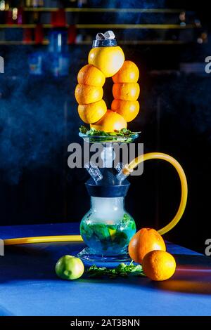 Hookah auf der Orange. Orange Hookah. Hookah mit einem runden durchsichtigen Kolben, in dem in Scheiben geschnittene Orangen und Minzblätter in roter Lauge schweben. Die Kapuzenbuge Stockfoto