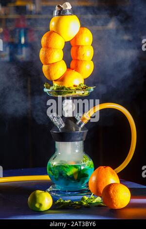 Hookah auf der Orange. Orange Hookah. Hookah mit einem runden durchsichtigen Kolben, in dem in Scheiben geschnittene Orangen und Minzblätter in roter Lauge schweben. Die Kapuzenbuge Stockfoto