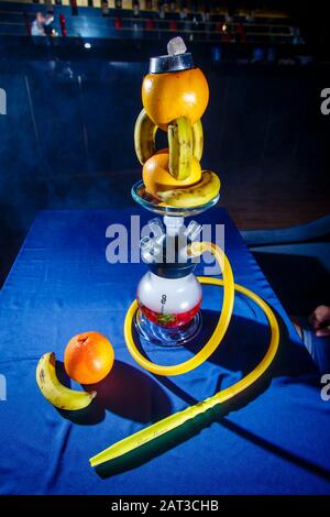 Hookah auf der Orange. Orange Hookah. Hookah mit einem runden durchsichtigen Kolben, in dem in Scheiben geschnittene Orangen und Minzblätter in roter Lauge schweben. Die Kapuzenbuge Stockfoto