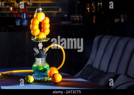 Hookah auf der Orange. Orange Hookah. Hookah mit einem runden durchsichtigen Kolben, in dem in Scheiben geschnittene Orangen und Minzblätter in roter Lauge schweben. Die Kapuzenbuge Stockfoto