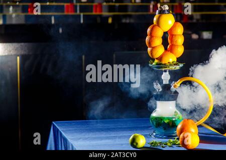 Hookah auf der Orange. Orange Hookah. Hookah mit einem runden durchsichtigen Kolben, in dem in Scheiben geschnittene Orangen und Minzblätter in roter Lauge schweben. Die Kapuzenbuge Stockfoto