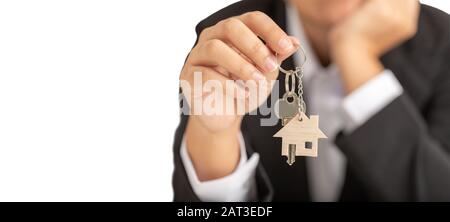 Die Frau benutzte eine Hand rechts, die ein simuliertes Holzhaus und davor stehende silberne Schlüssel hielt. Stockfoto