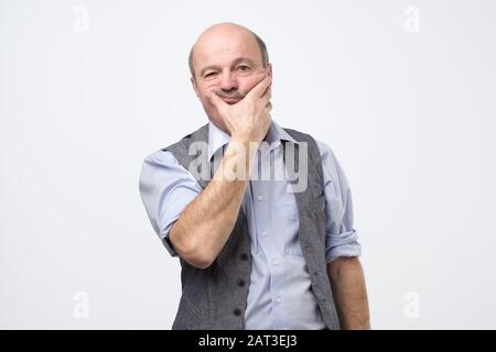 Der ältere hispanische alte Mann im Hemd und Weste denkt und sieht nachdenklich mit nachdenklichem Gesicht nachdenklich aus. Gesichtsausdruckkonzept isoliert auf weißem Hintergrund. Stockfoto