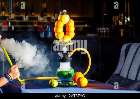 Hookah auf der Orange. Orange Hookah. Hookah mit einem runden durchsichtigen Kolben, in dem in Scheiben geschnittene Orangen und Minzblätter in roter Lauge schweben. Die Kapuzenbuge Stockfoto