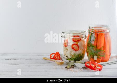 Zwei Glasgefäße aus fermentiertem Blumenkohl, Karotten, Gemüse auf hellem Hintergrund. Mit Textilhellgrau. Fermentation ist eine Quelle für Probiotika. Stockfoto