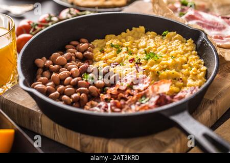 Komplettes englisches Frühstück. Rührei gegrillte Speckbohnen Toast Brot Orangensaft und Kaffee Stockfoto