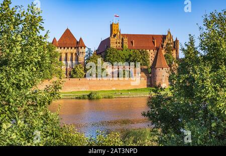 Malbork, Pomerania/Polen - 2019/08/24: Panoramaaussicht auf die Verteidigungsmauern und Türme der mittelalterlichen Burg des Deutschen Orden in Malbork, Polen, über den Fluss Nogat Stockfoto