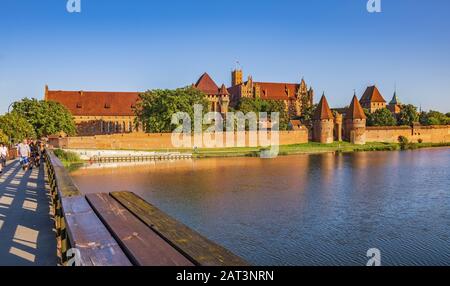 Malbork, Pomerania/Polen - 2019/08/24: Panoramaaussicht auf die Verteidigungsmauern und Türme des mittelalterlichen Schlosses des Deutschen Orden in Malbork, Polen mit der St. Wojciech-Brücke über den Nogat-Fluss Stockfoto