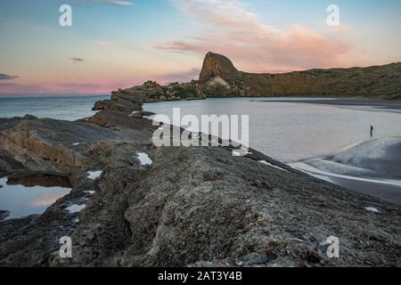 Malerische Aussicht auf Castlepoint-Klippen, Felsen und Lagune von Treppen bei Sonnenuntergang mit blauem, pinkfarbenem und violettem Himmel. Nordinsel, Neuseeland Stockfoto