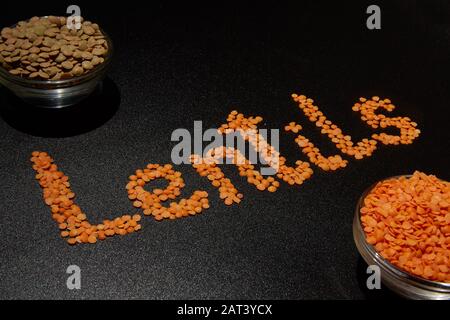 Zwei Arten von Getreidelinsen auf dunklem Hintergrund und das Wort "Linsen" auf Englisch Stockfoto