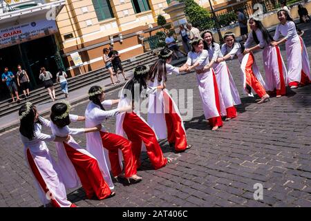 Gruppe von Mädchen in Ao Dai das traditionelle Kleid, das Tauziehen des Krieges außerhalb der zentralen Post, Ho-Chi-Minh-Stadt, Vietnam spielt Stockfoto