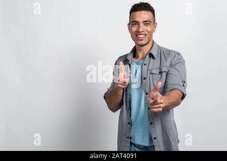 Glücklicher Mulatto Mann lächelt und zeigt auf Kamera, Geste von seinen Fingern - Bild Stockfoto
