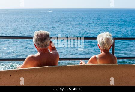 KANARENINSEL TENERA, SPANIEN - 27 DEC, 2019: Ein pensionierter Ehepaare sitzt auf einer Bank, die die Sonne und den Blick auf Teneras genießt. Stockfoto