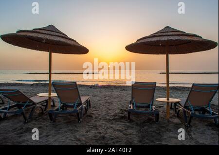 Zwei liegen an einem leeren Strand kurz vor Sonnenuntergang. Stockfoto