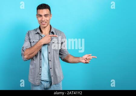 Fröhlicher Mulatto Mann lächelnd und mit dem Sideaway zeigt Geste von seinen Fingern - Bild Stockfoto