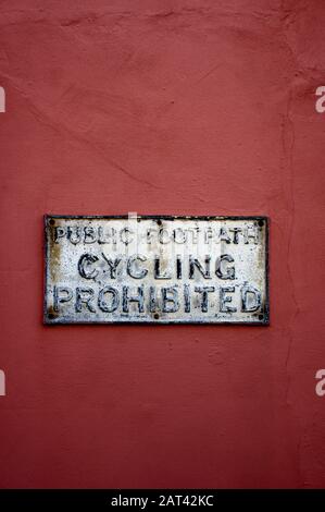 Ein altes Schild an einer Wand, das das Fahrradfahren untersagt Stockfoto