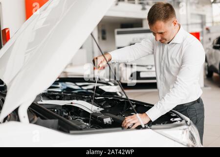 Der Mann kontrolliert das Vorhandensein von Öl in der Nähe des Fahrzeugs Stockfoto