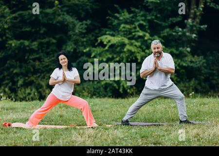Paare im mittleren Alter, die Yoga stehen und Geste namaste machen - Konzept Yoga - Bild Stockfoto