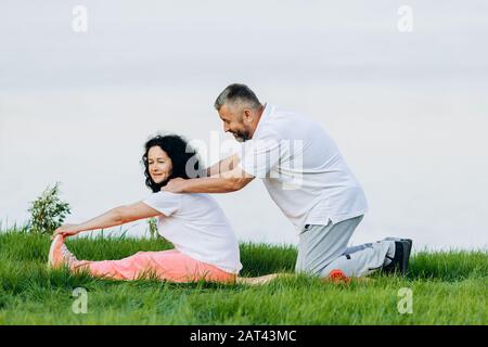 Glückliche ältere Frau, die im Freien Sport macht und Mann, der für sie Massage tut - Bild Stockfoto