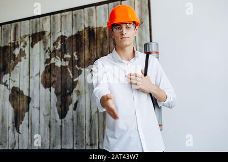 Lächelnder, gutaussehender Architekt mit einem Hut, der ein Rohr hält. Stockfoto