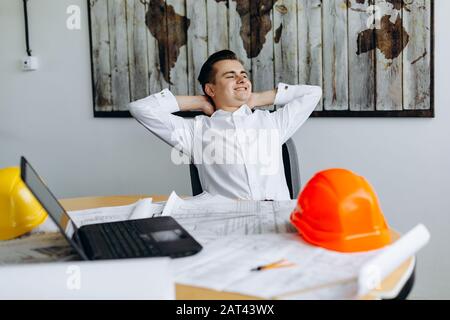 Fröhlicher junger Geschäftsmann, der sich in seinem Stuhl zurücklehnt Stockfoto