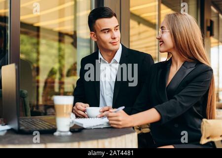Ein Paar im Café, das während des Abendessens am Laptop arbeitet und sich gegenseitig betrachtet.- Bild Stockfoto